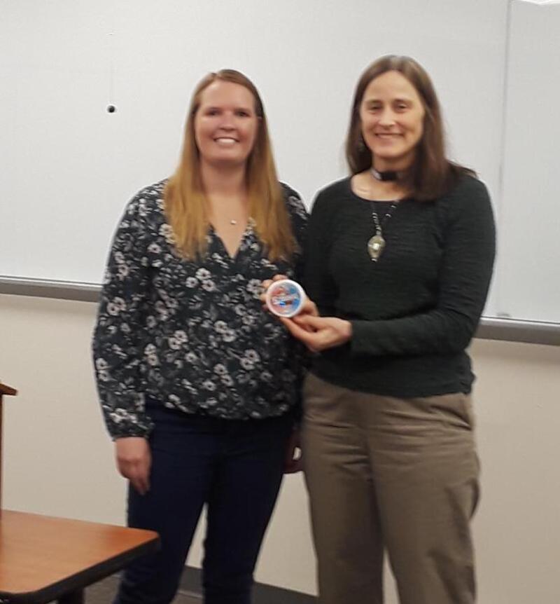 One woman presenting the other an award for completing an ice breaker speech